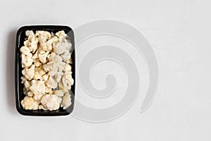 Frozen cauliflower in a plastic container on a white background. Healthy frozen vegetables. Copy space, top view, flat lay