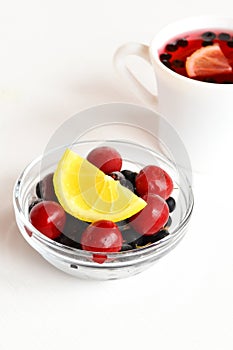Frozen cherries and black currants, a slice of fresh lemon, Cup of compote