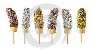 Frozen chocolate dipped banana pops with an assortment of sprinkles, nuts and coconut isolated on white