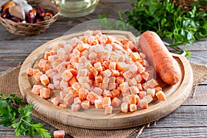 Frozen chopped carrot cubes on a cutting board on a table