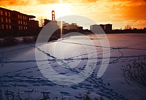 Frozen city pond during dramatic sunset background