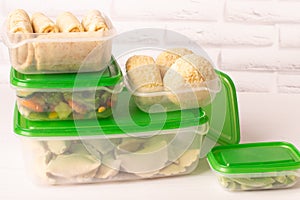 Frozen convenience foods and vegetables in plastic containers on a white table