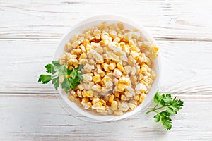 Frozen corn in a plate on white table. Frozen food. Top view. Copy space