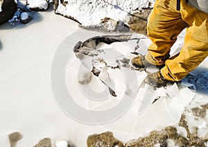 Frozen and craked ice below the boots of a man