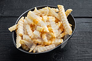 Frozen crinkle oven fries, on black wooden table background