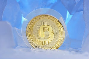 Frozen crypto currency bitcoin face obverse stands surrounded by blue ice in beautiful light.