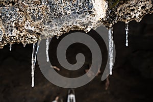 Frozen dripping water on the stone entrance of antique cave in winter