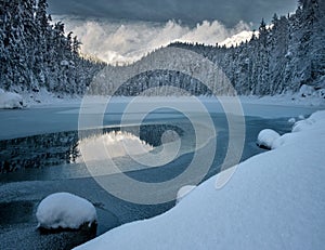 Frozen Eibsee river surrounded by trees covered with snow in Bavaria, Germany