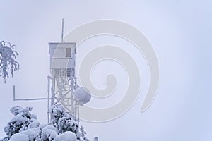 Frozen fire tower against white overcast sky in winter