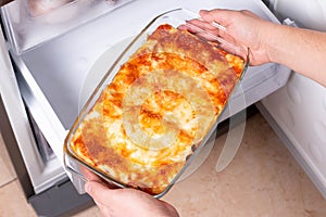 Frozen food. Man`s hands are taking frozen lasagna from the freezer. Concept of ready made frozen dishes and saving time on