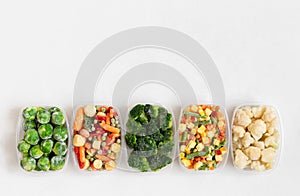 Frozen food vegetables mix in containers on white background. Copy space, view from above