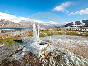 Frozen fountain on mountain landscape with snowed cap