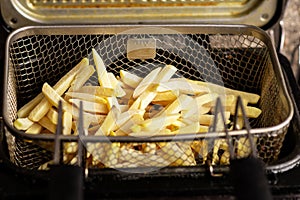Frozen french fries in a fryer basket. Semi-finished product from frozen potatoes. Preparing for frying