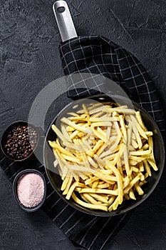 Frozen French fries in a frying pan. Black background. Top view. Space for text