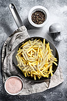 Frozen French fries in a frying pan. Gray background. Top view