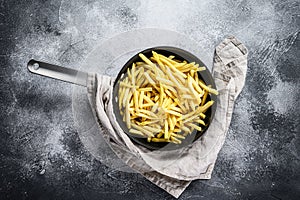 Frozen French fries in a frying pan. Gray  background. Top view. Space for text