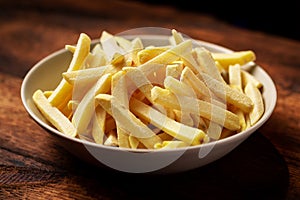 Frozen french fries on a plate on a wooden background. Semi-finished product from frozen potatoes