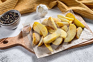 Frozen French Fries potato wedges on a wooden cutting board. White background. Top view