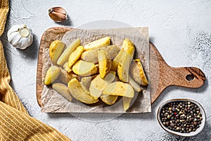 Frozen French Fries potato wedges on a wooden cutting board. White background. Top view