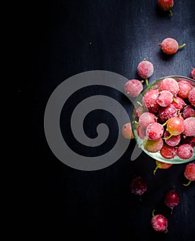 Frozen and fresh berries in a glass pial on a black background.