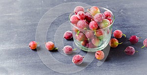 Frozen and fresh berries in a glass pial on a black background.