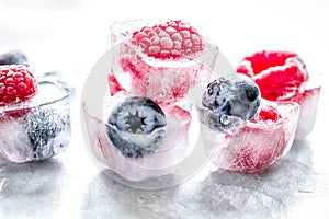 Fresh blueberry and raspberry in ice on table background