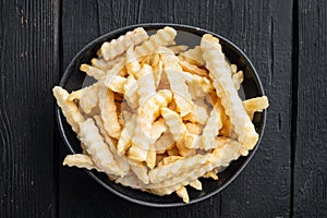 Frozen fries, on black wooden table background, top view flat lay