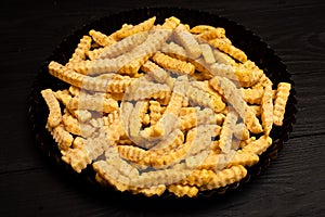 Frozen fries with spices on a black background. Preparation for cooking