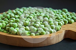 frozen frosty green peas on wooden plate closeup