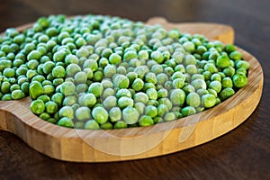 frozen frosty green peas on wooden plate closeup