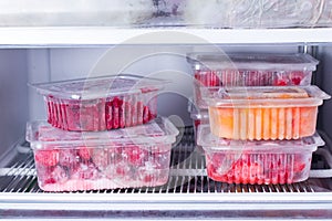 Frozen fruits and berries in a container in the freezer