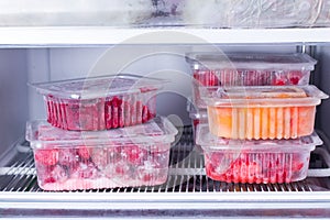 Frozen fruits and berries in a container in the freezer photo