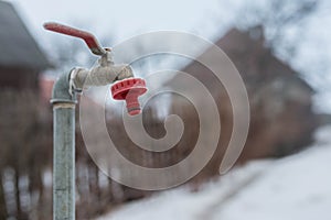 Frozen garden water tap on a cold winter morning, shallow depth of field