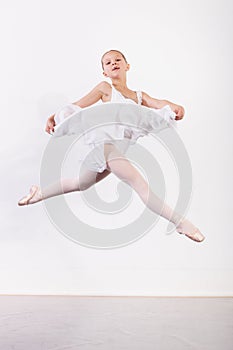 Frozen grace. a young ballerina energetically leaping across the floor of a dance studio.