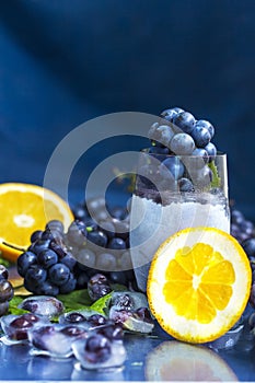 Frozen grapes in glass with orange and ice close-up