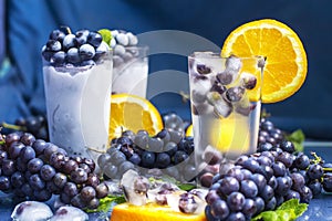 Frozen grapes in glass of water with orange and ice close-up