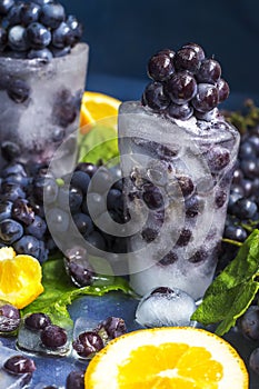 Frozen grapes in ice with orange close-up