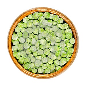 Frozen green peas, seeds of Pisum sativum in wooden bowl