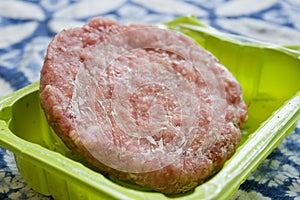 Frozen hamburger in a plastic tub