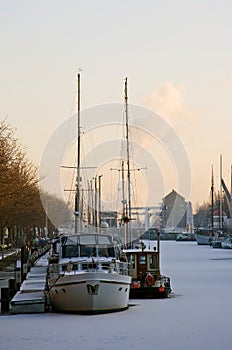 Frozen harbour with ships in winter at sunset