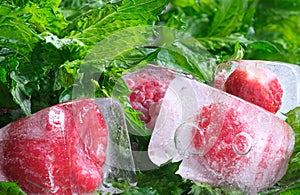 frozen in ice raspberries and strawberries and green fresh mint leaves close-up