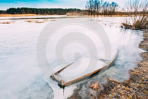 Frozen Into Ice Of River, Lake Old Wooden Boat. Abandoned Rowing