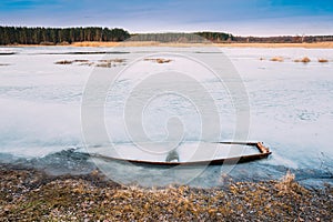 Frozen into ice of river, lake, pond old wooden boat. Forsaken r