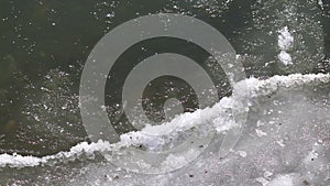 Frozen ice river is melting in spring with ice flakes flowing. Cracked ice floating on the river in spring time. Global warming.