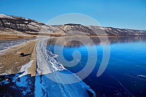 Frozen Lake Baikal. View of the transparent ice on a sunny January day. Winter travel in Russia