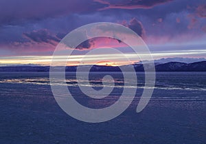 The frozen Lake Baikal. Winter landscape with tranparent ice and snow near the rocks of Olkhon Island in the sunset