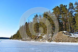 Frozen lake, dense forest and rocky shore