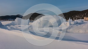 On a frozen lake, icy snow forms bizarre figures.