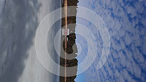 Frozen lake or sea melting in the spring. Blue sky with unusually shaped soft clouds and forested islands in the distance. Finnish