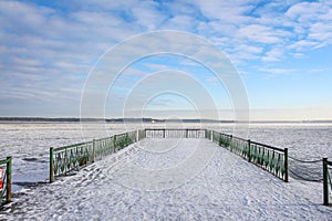 Frozen lake seen from the snowy pier on a chilly day.